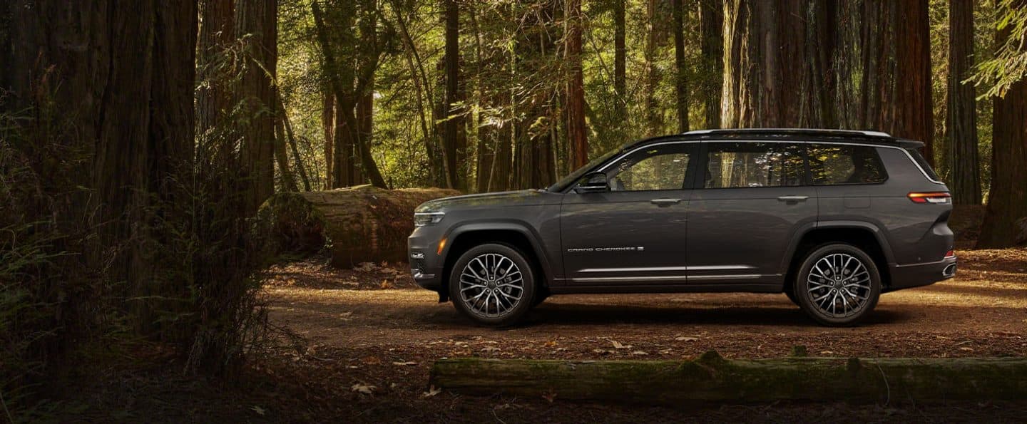 El perfil del lado del conductor de un Jeep Grand Cherokee L Summit Reserve 2024 estacionado en un bosque.